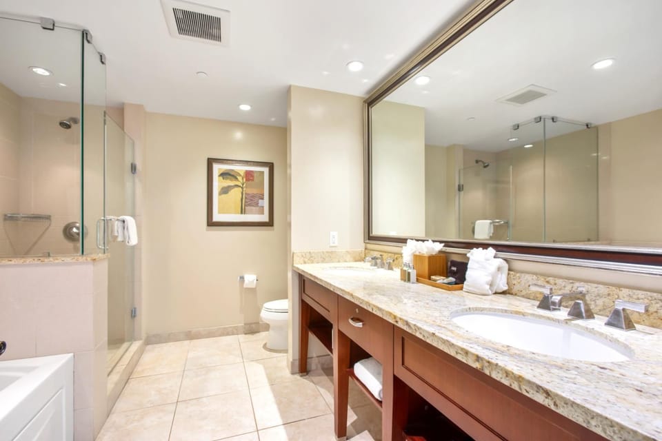 Elegant bathroom with granite counters, glass shower, and tropical decor.