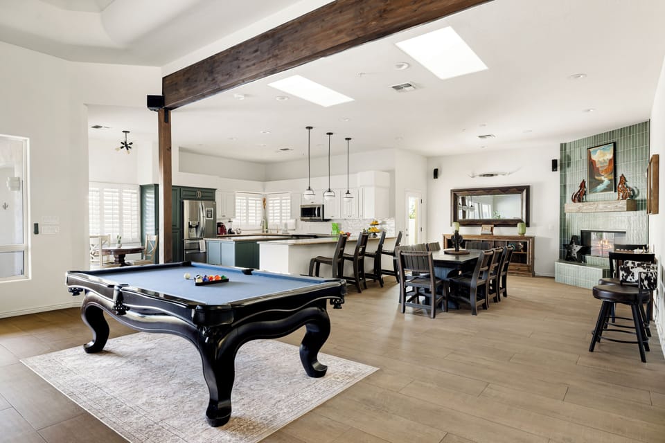 Open concept entertainment space with a pool table, dining area, fireplace, and seamless connection to the chef's kitchen.