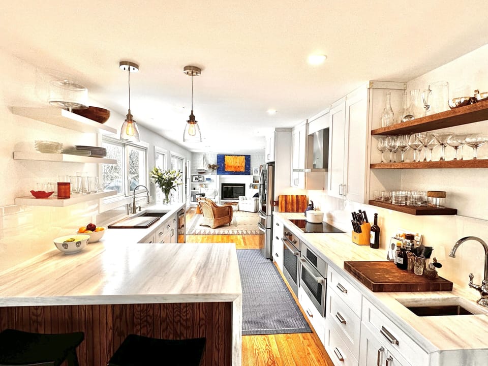 Open-concept kitchen clad in imported white marble and stainless steel appliance by Bosch & LG