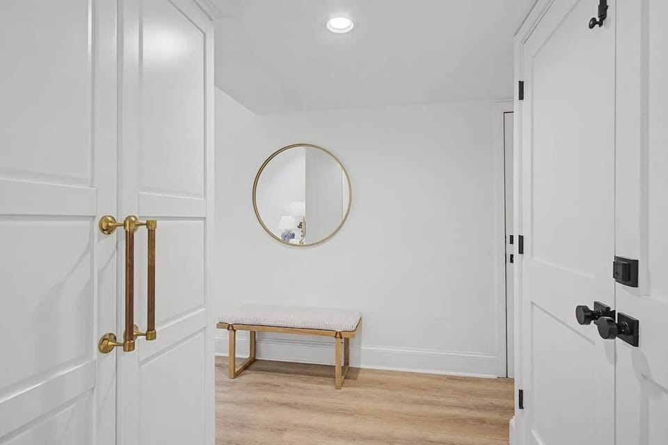 Entryway with a round mirror and wooden bench on light hardwood floors