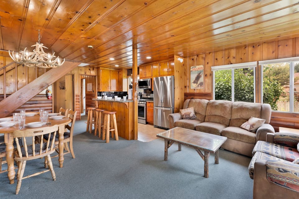 Cozy mountain living room with a stone fireplace, comfy seating, and smart TV—perfect for relaxing evenings, movie nights, and warm cabin vibes after outdoor adventures.