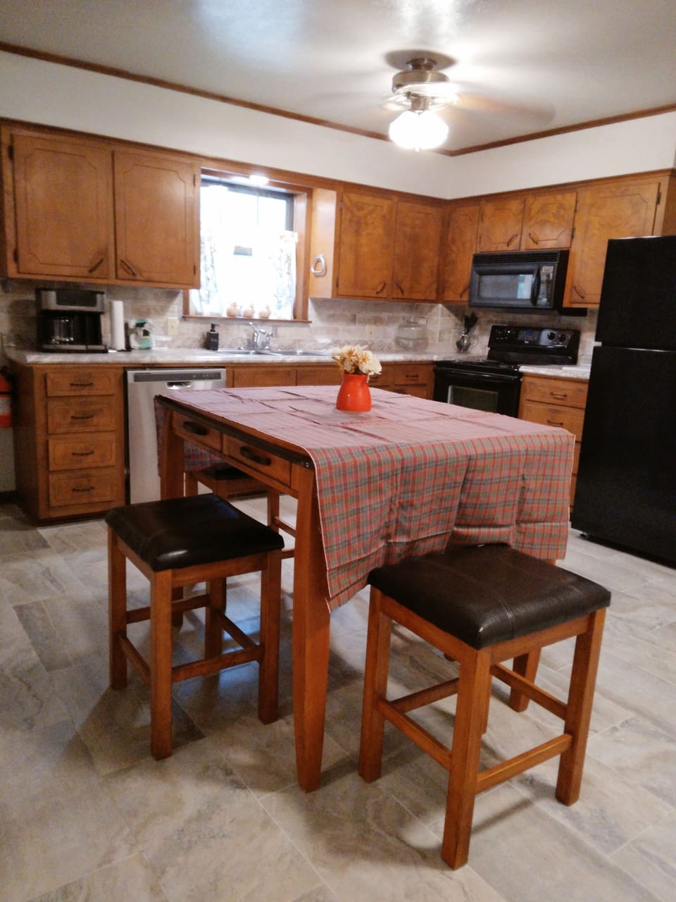 Kitchen w table and 4 chairs, fridge, microwave, stove, dishwasher, and dishes.