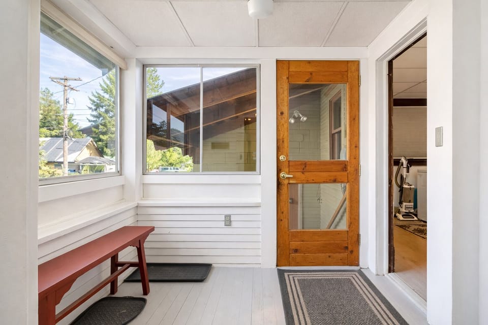 Your bright entryway welcomes you with charming wood-and-glass doors, cozy seating, and peaceful neighborhood views through large windows.