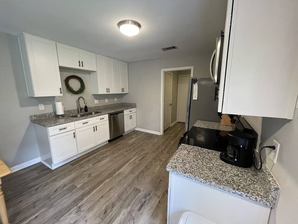 Full kitchen equipped with dishes, cookware, coffee pot, and utensils.