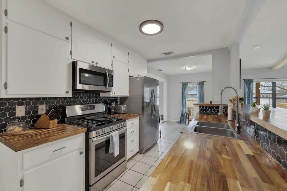 The fully stocked kitchen features a gas stove, side-by-side refrigerator, microwave, toaster, cookware, utensils, and tableware.
