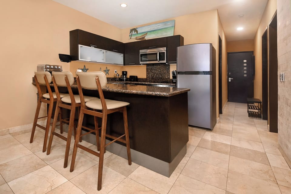 Gather around the spacious granite-topped island to cook and connect. This fully equipped kitchen offers modern appliances, sleek cabinetry, and bar seating for easy entertaining or morning coffee.