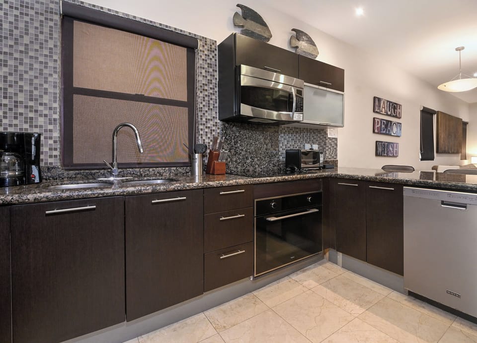 A sleek, fully equipped kitchen awaits you with modern appliances, granite countertops, and stylish mosaic tile backsplash—perfect for preparing your favorite meals during your stay.
