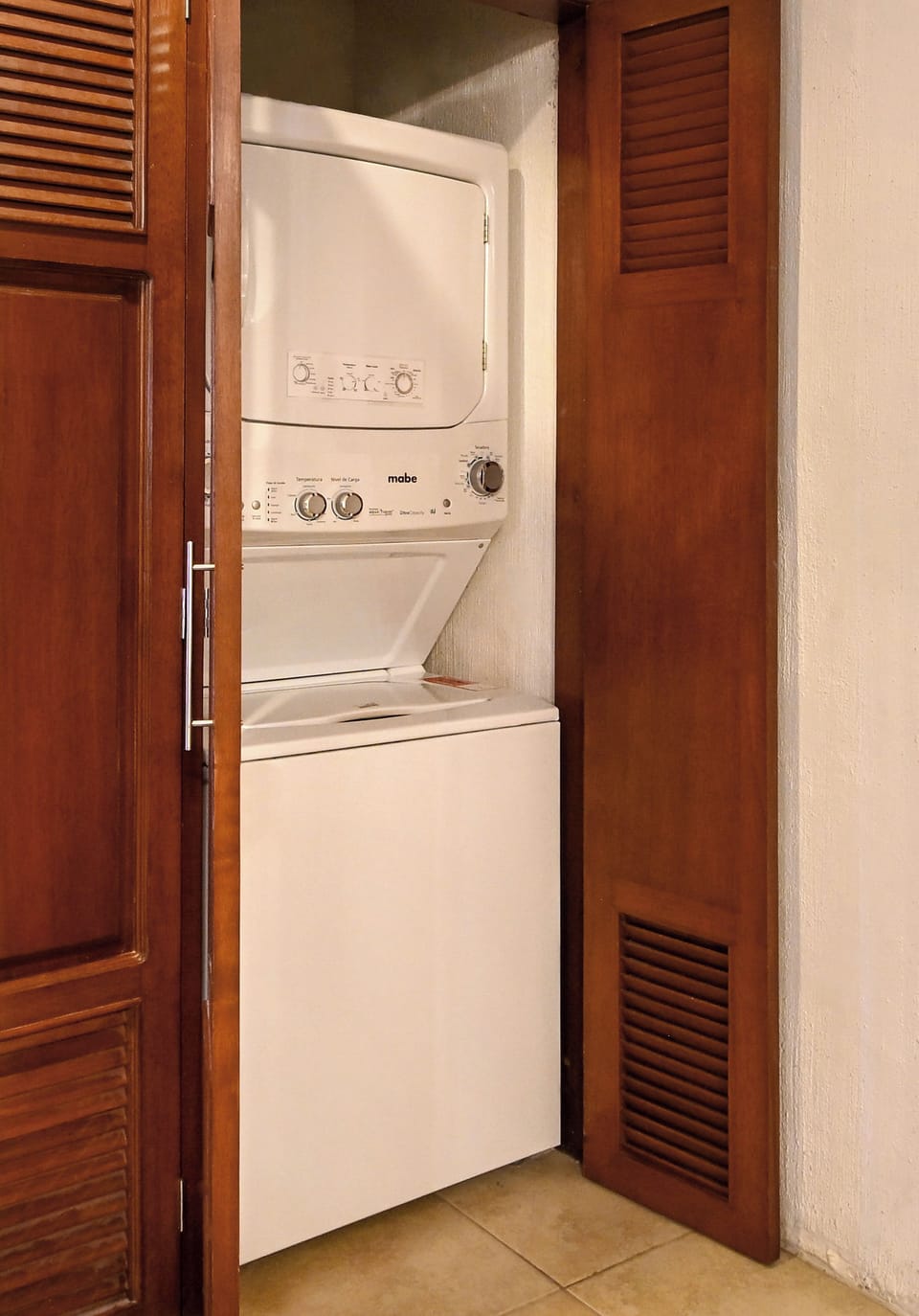 Your laundry is conveniently tucked away behind elegant louvered doors, with a stacked washer and dryer ready whenever you need them.