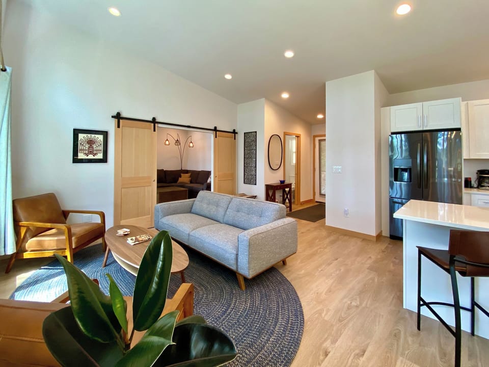 Sun-drenched open living with mid-century style, sliding barn door, and a fully equipped kitchen just steps away