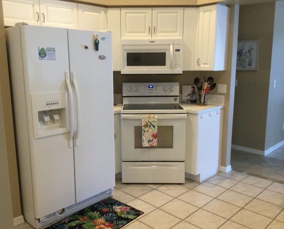 Kitchen containing pantry, refrigerator, microwave, and range/oven.