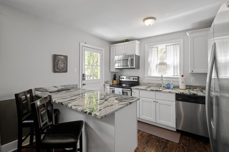 Sleek marble countertops, modern appliances, and a spacious kitchen island bar with stool seating.