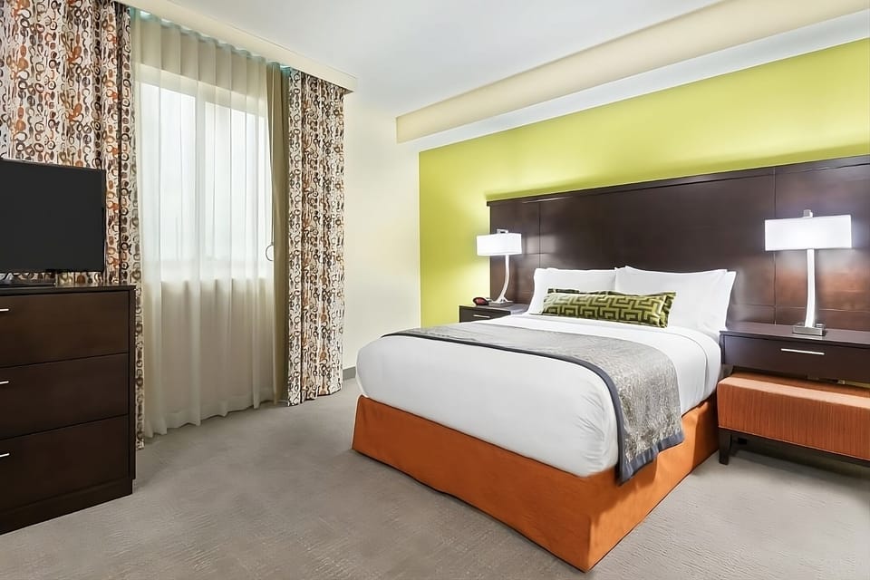 Unwind in a crisp, sunlit bedroom with plush bedding.
