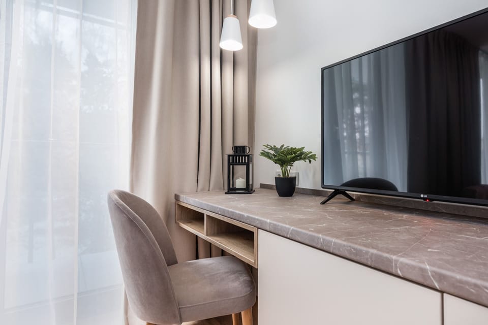 A spacious workspace with a sleek desk, a large window, and light curtains for natural lighting.
