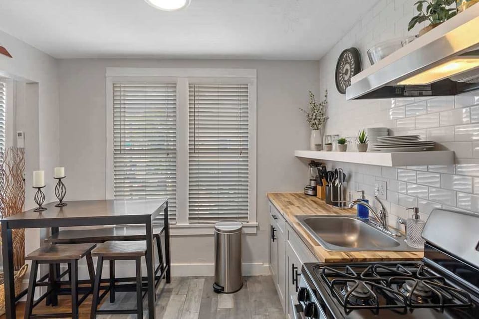The kitchen has a gas stove and a dining table. 