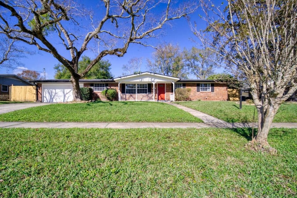Inviting ranch-style home with a classic brick exterior, spacious front yard, and a cozy covered porch.