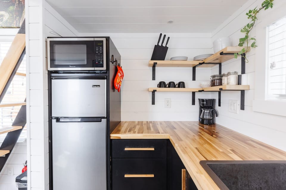 The kitchen is fully equipped with a refrigerator, freezer, microwave, cooktop, and sink with hot/cold water. Enjoy coffee from the coffee maker and ample counter space. Essentials include cookware, dishes, utensils, and plenty of storage cabinets.