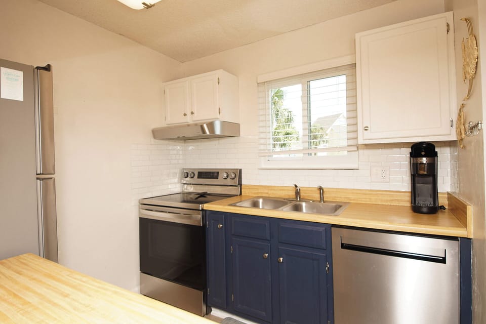 Your fully equipped kitchen features modern appliances and charming blue cabinetry, perfect for preparing meals with natural light streaming in.