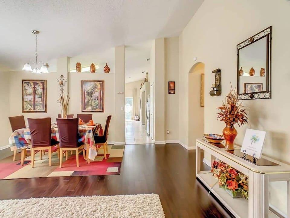Showcasing a dining area with a table and chairs, and an entryway with decorative elements. The dark wood flooring and neutral wall colors create a warm and inviting atmosphere.