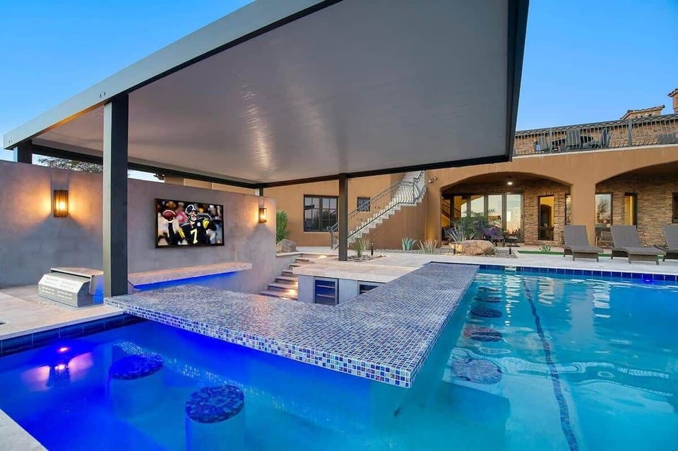 Cool off at the covered swim-up bar with 65" TV and fridge