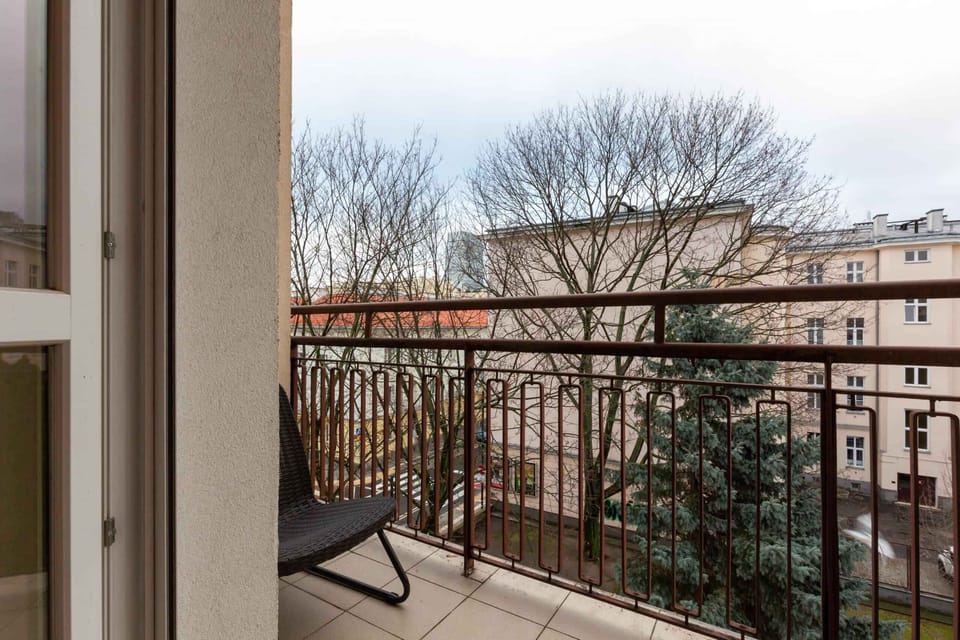 A balcony view overlooking a serene residential area with trees and open spaces.
