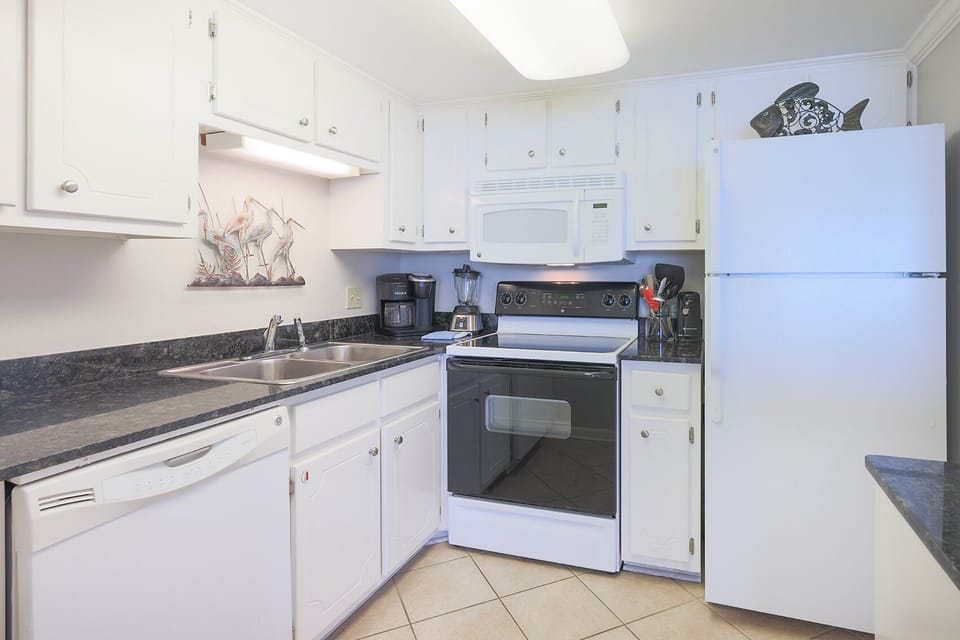 This kitchen features white cabinetry, sleek countertops, and essential appliances for a delightful cooking experience