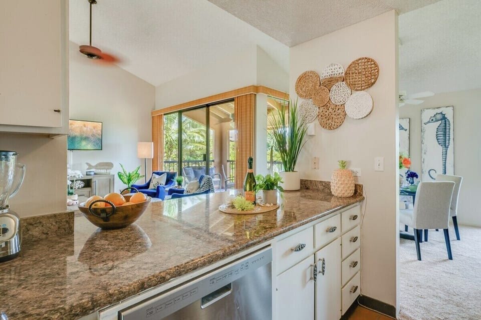 Granite counters stretch wide, fruit bowls and blue accents adding warmth.