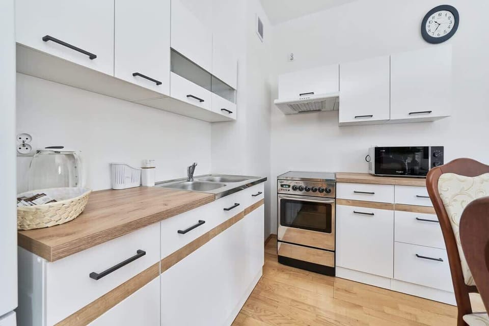 A fully equipped kitchen with modern appliances, a clean design, and white cabinets.
