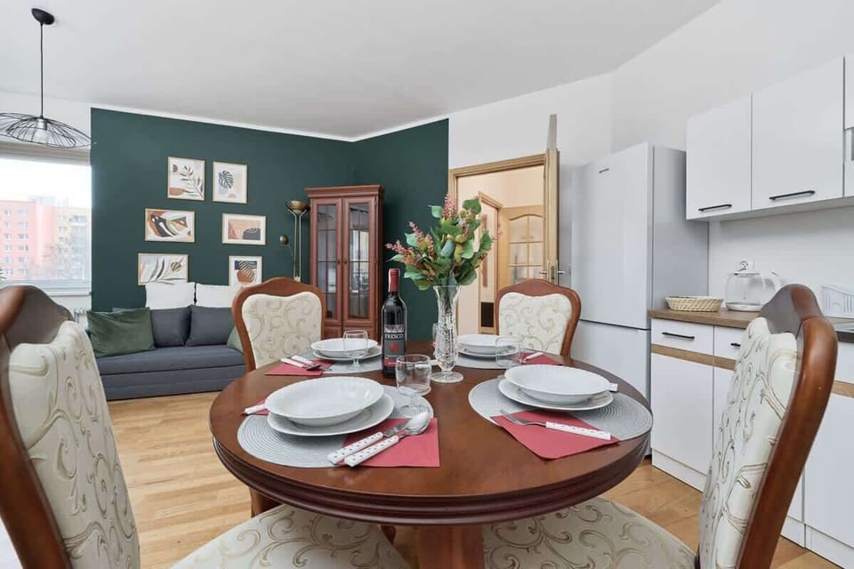 A well-lit dining corner with a round table and elegant table settings.
