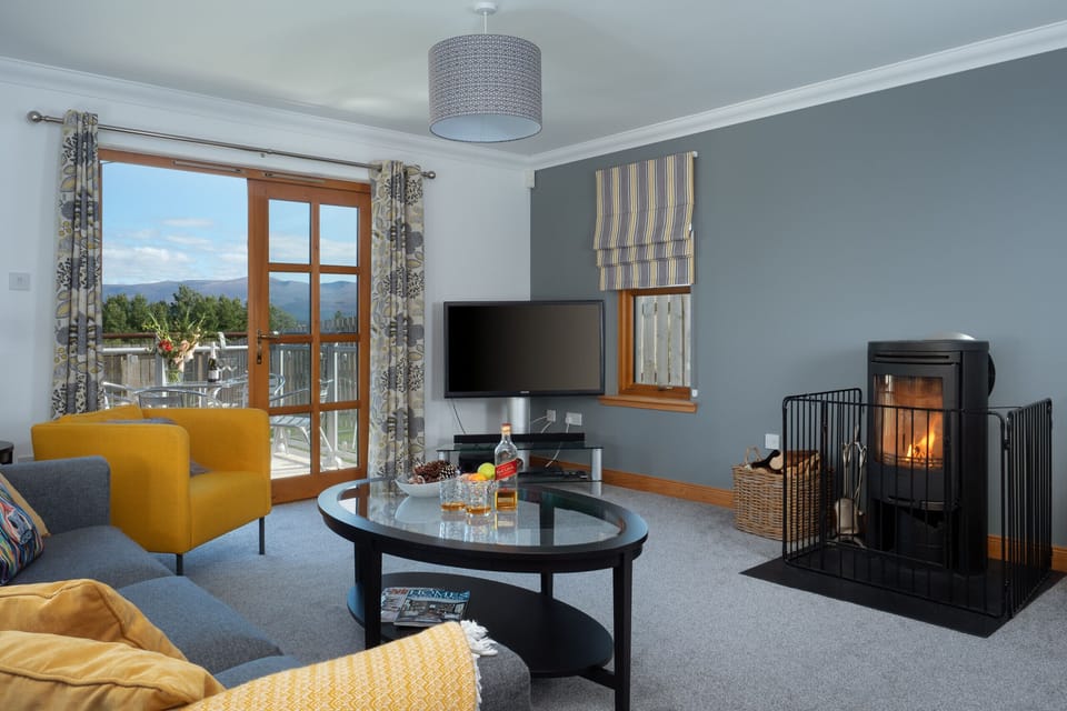 Living room with smart tv and log burner - perfect for cosy nights in. French doors open to dedcking.