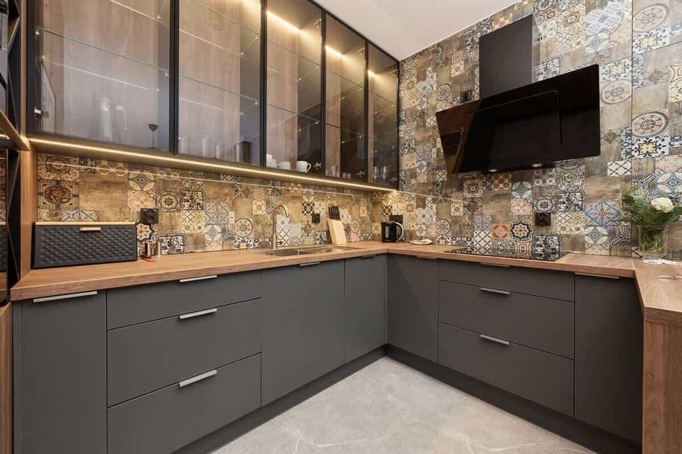 A modern kitchen with wood and black cabinetry, colorful patterned tiles as a backsplash, and high-end appliances.