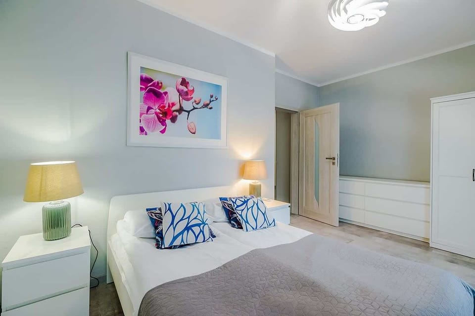 A comfortable bedroom with a large bed, soft lighting, and blue accents, creating a relaxing atmosphere.