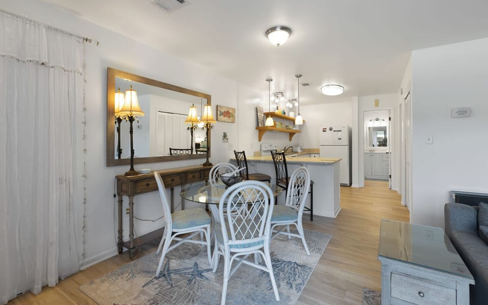 Step into your bright dining space where coastal charm meets comfort—perfect for sharing meals around the glass table.