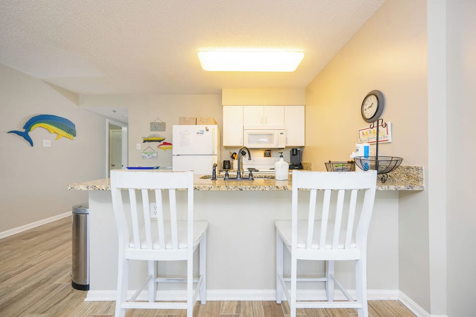 The kitchen invites you to prepare meals while sitting at the breakfast bar with sea-inspired decor nearby