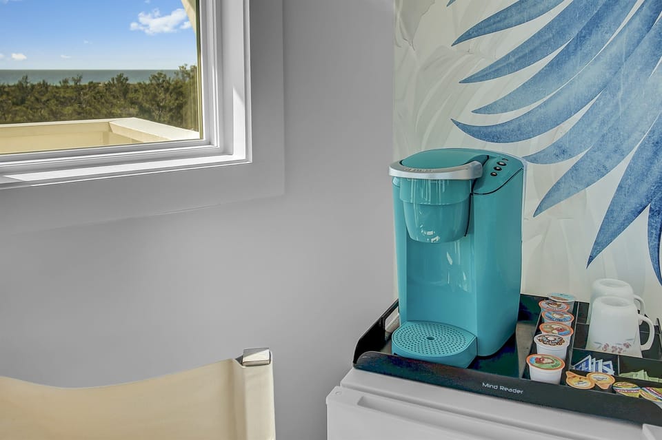 Fourth Floor Crow's Nest - a haven for relaxation and breathtaking views. Adorned with modern coastal decor, this space bathes in abundant natural light. Step out onto the small balcony for sunrise or sunset views. Mini fridge and Keuring also provided.