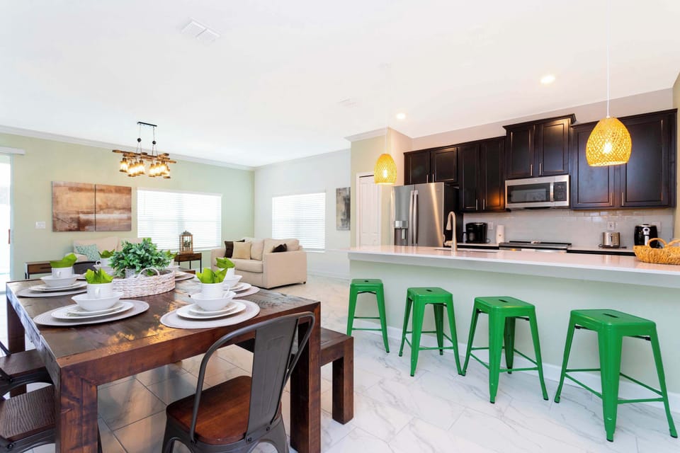 Open-concept kitchen and dining space with rustic wood table, bright living area, and fun green bar stools-perfect for gathering and sharing meals!