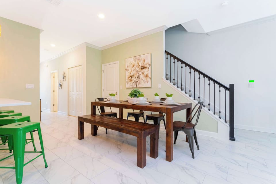 Open dining area with a rustic wood table, bench seating, and airy staircase views-perfect for gathering with family and friends.