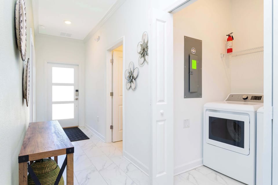 Bright hallway with sleek tile flooring and a handy laundry nook-an easy, modern space that keeps your stay comfortable and organized.