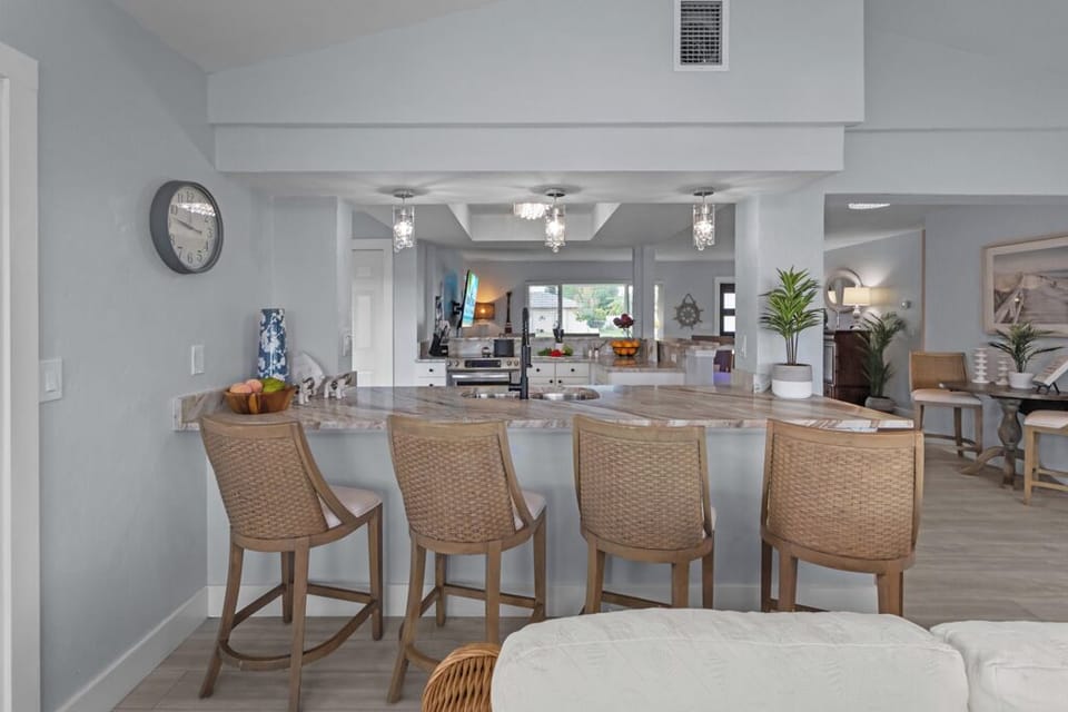 Bright and inviting kitchen featuring crisp white cabinetry, sleek stainless steel appliances, and a spacious wrap-around breakfast bar perfect for casual dining and entertaining.