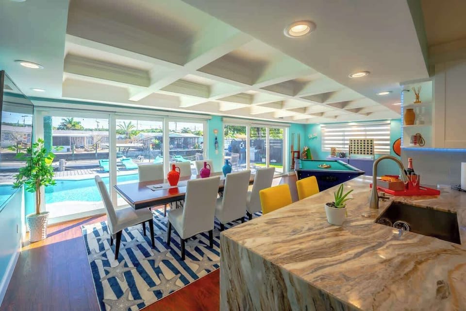 The updated kitchen is equipped with stainless steel appliances and granite waterfall countertops. The open concept allows you to overlook the pool deck and canal. Exposed wooden beams in the sunroom add to the modern but warm feel. 