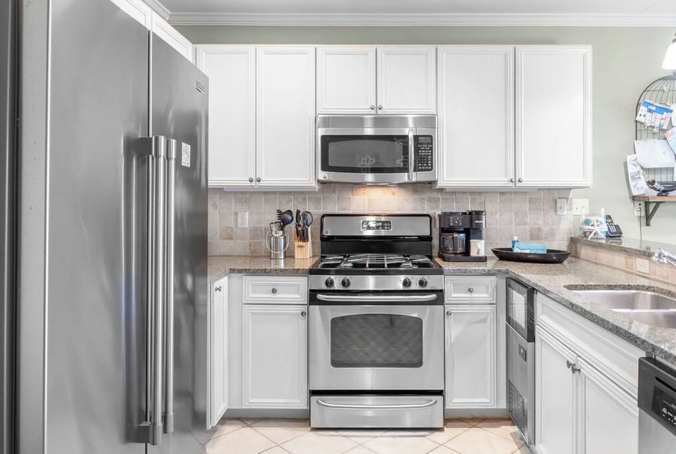 Kitchen - The fully stocked kitchen features stainless appliances which include a dishwasher, beverage cooler, ice maker, gas range, built in microwave, and large side by side refrigerator freezer. Fully stocked cabinetry that offers all things needed for preparing meals during your stay.