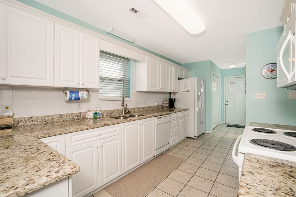 Your fully-equipped kitchen awaits with granite countertops, white cabinetry, and modern appliances for preparing memorable meals during your stay.