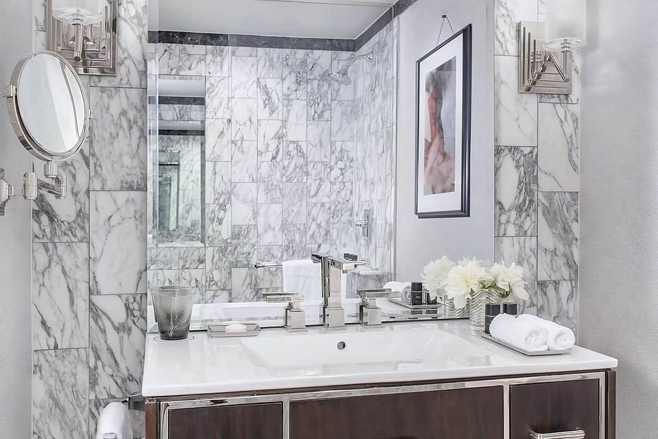 Refresh at a marble vanity with bright, spa-like lighting.