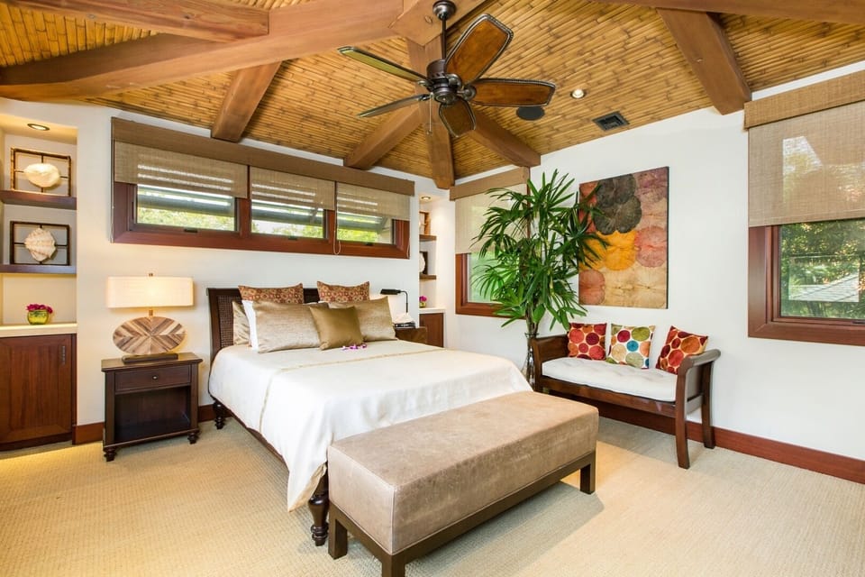 The upstairs guest room offers a peaceful retreat with warm wood ceilings, natural light, and island-inspired design.