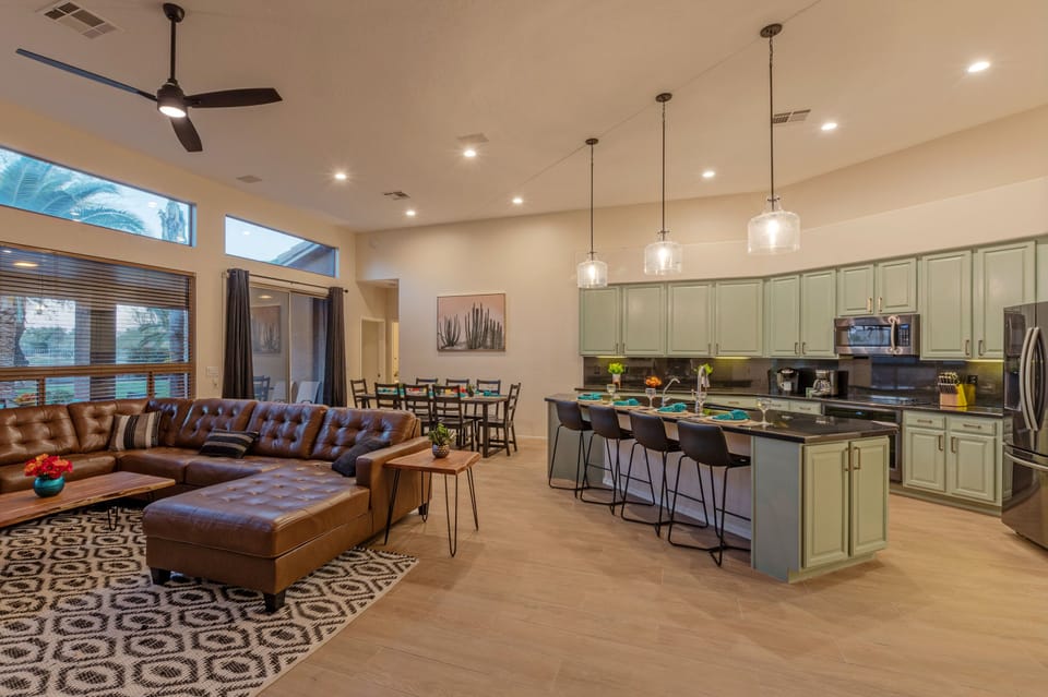 An open and spacious great room features a cozy gathering area, a kitchen with island seating plus a dining area with table seating.