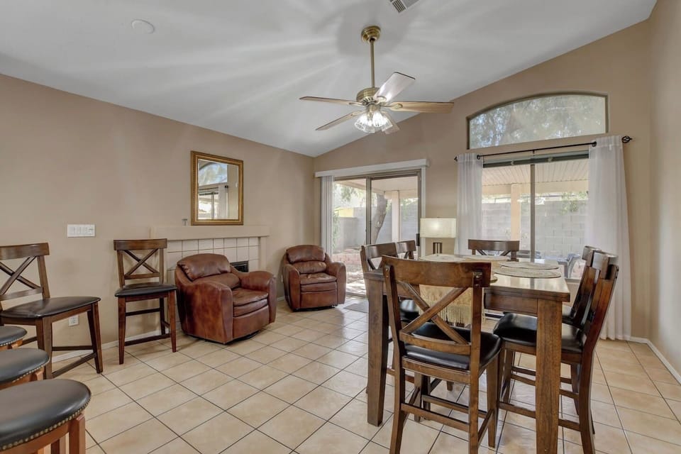 Sunny dining nook with patio access, recliners, and vaulted ceiling.