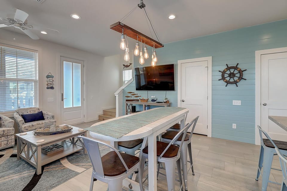 You'll love gathering around this stylish dining table beneath the warm Edison bulb chandelier, with coastal accents creating the perfect atmosphere.