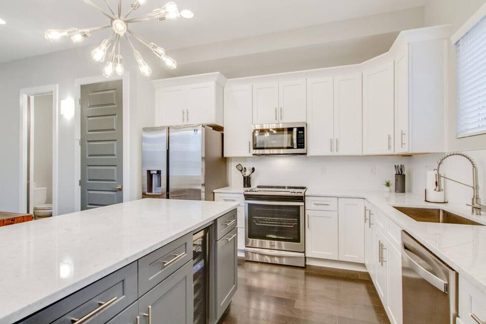 Bright white kitchen with stainless steel appliances and a spacious island
