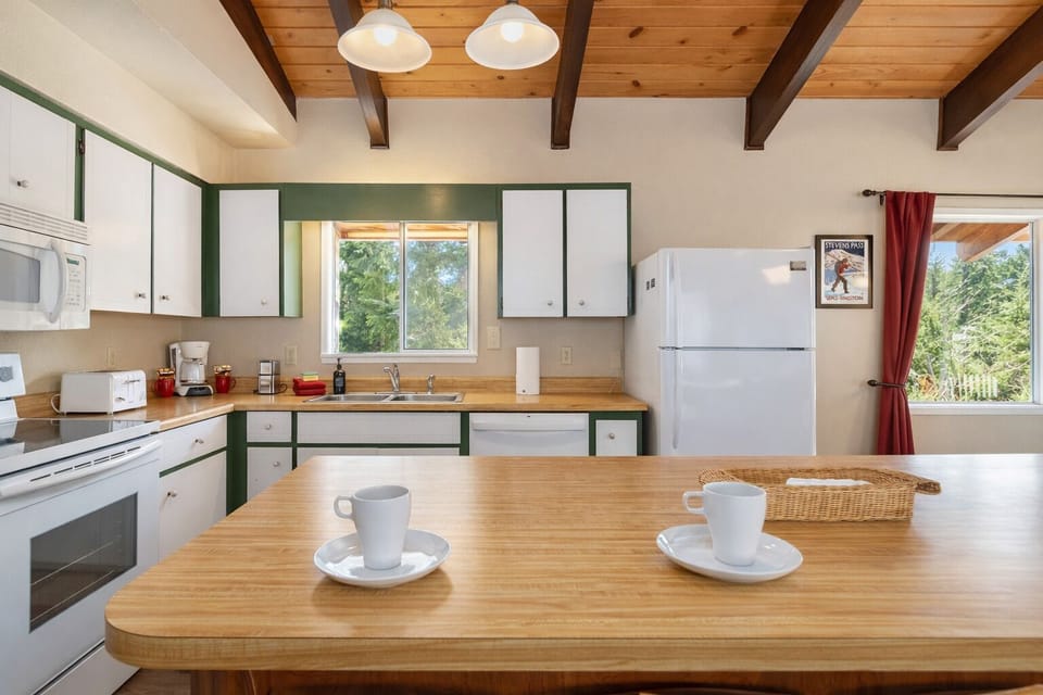 Your bright kitchen invites morning coffee moments with exposed beam ceilings, wood counters, and garden views through cheerful windows.