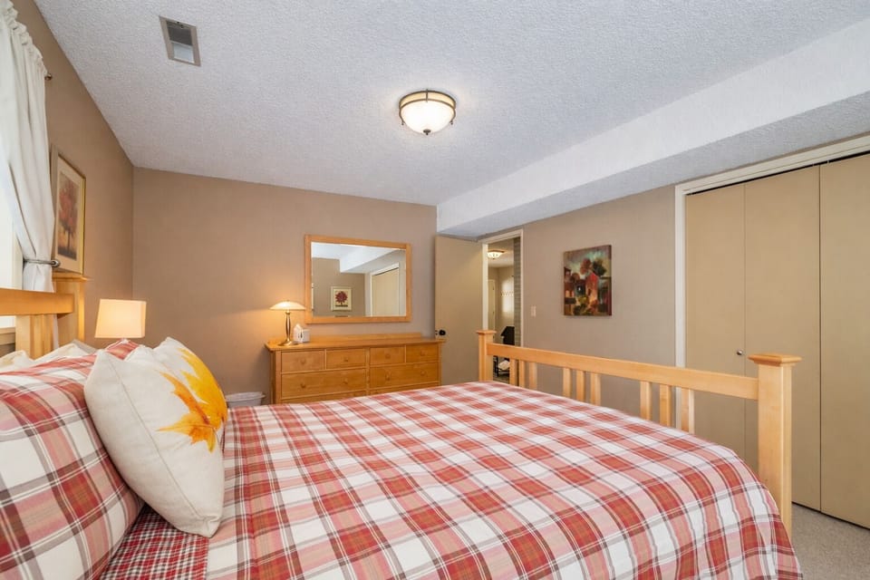 Your cozy bedroom features warm plaid bedding, natural wood furnishings, and thoughtful touches that make you feel right at home.