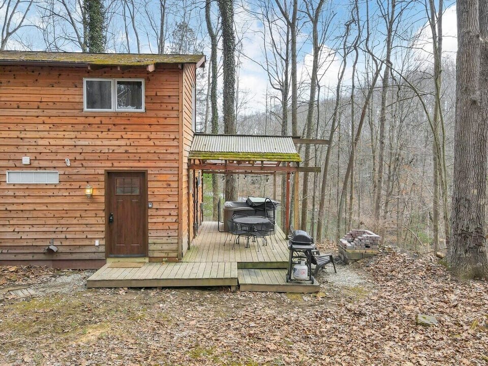 Deck off the side of the cabin with seating, a grill, fire pit area, and hot tub